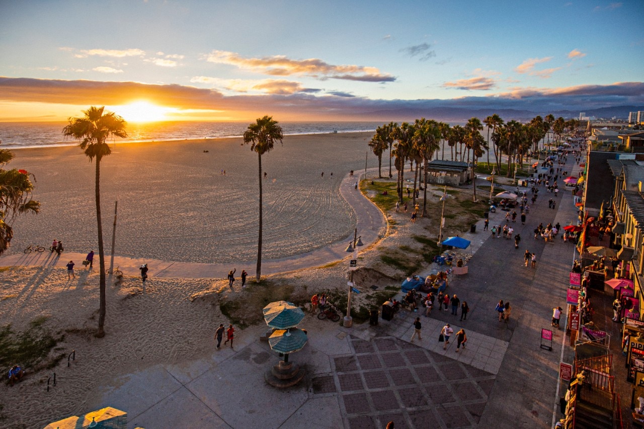 638340372 High angle view of Venice beach during sunset. Tourists are walking on footpath by ocean. Shot of beautiful nature and people is taken from above.