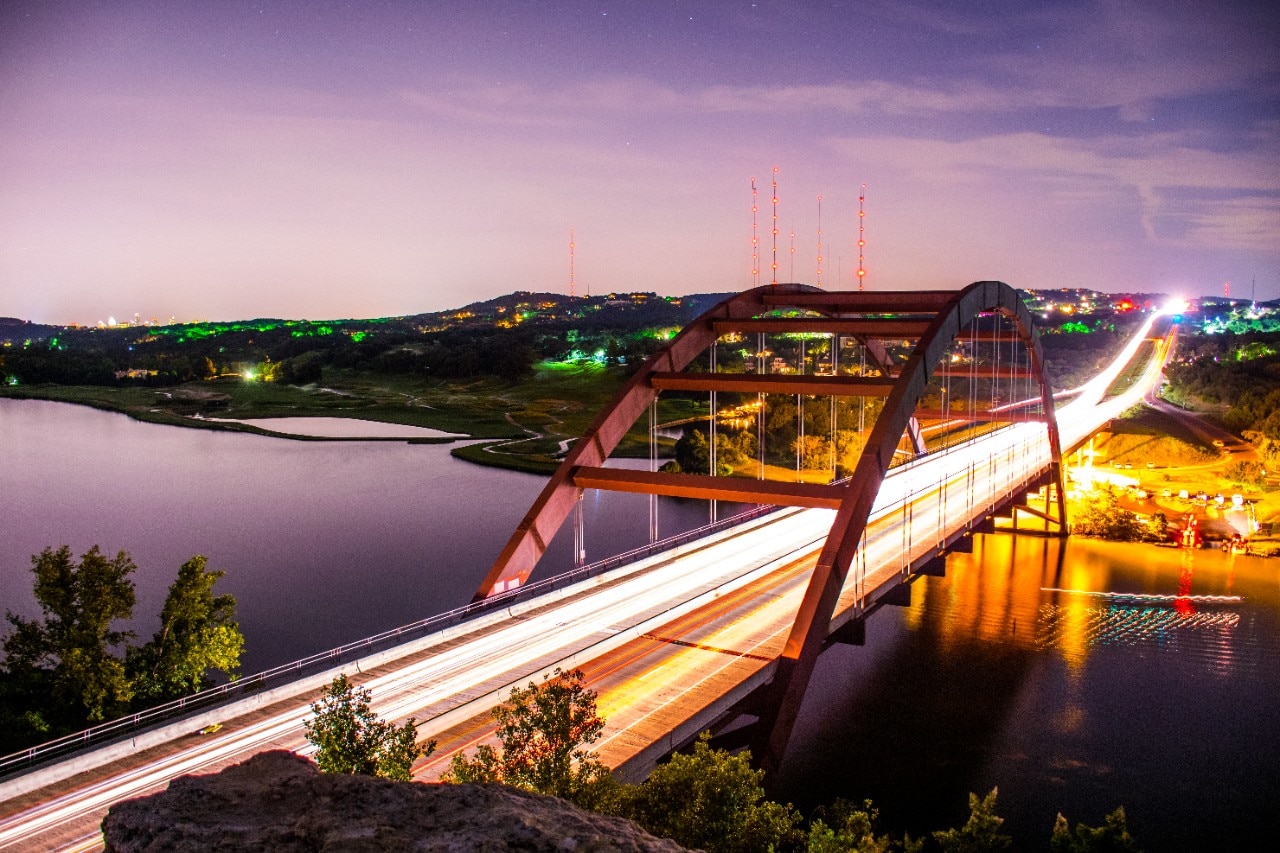 Austin Texas Landmark Pennybacker Bridge 360 Bridge At Night. On special night the bridge lights up with activity . driving cars , boats driving by , the headlights and brakelights , mixed with the long exposure give off an artistic view of the central Texas hill country and the colorado river combined with the Pennybacker Bridge gives one of the most amazing Landscape views in all of Texas. 