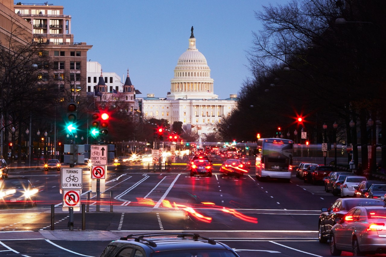 US Capitol building illuminated at night with Pennsylvania Avenue in foreground